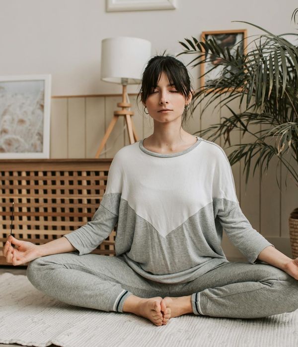 Woman in a peaceful yoga pose, bathed in soft light.